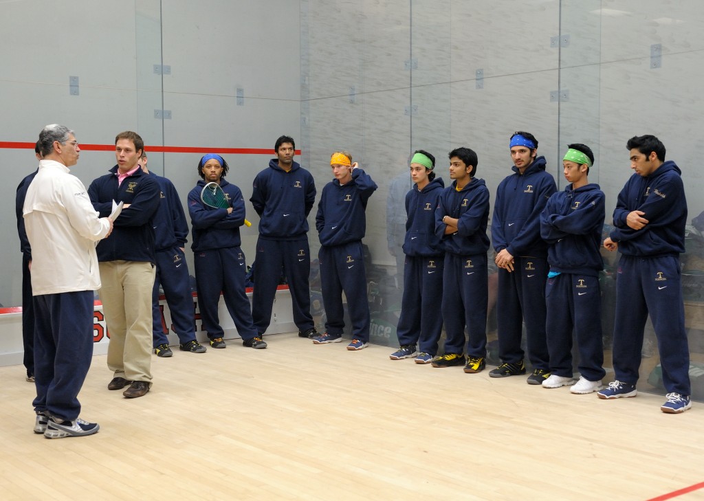 Coach Paul Assaiainte comiserates with his assistants just before the championship match against Princeton, while the Trinity men await their introductions. (L-R) Assaiante (in white), David Jones (Asst. Coach), Simba Muhwati, Baset Chaudhry, Gustav Detter, Andres Vargas, Parth Sharma, Supreet Singh, Randy Lim, and Rushabh Vora.