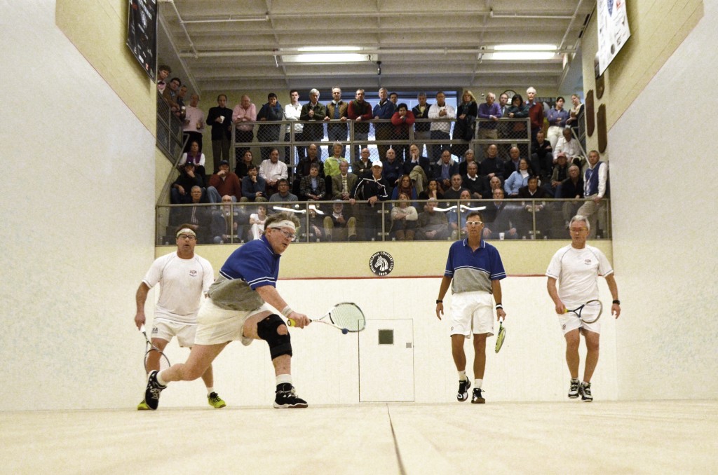 The PCC gallery filled to the brim for the men’s 50+ final. The men in blue, Ed Chilton (center, right) & Andrew Slater (center, left) went on to win their first 50+ title against defending champions Dominic Hughes (far right) Rich Sheppard. 