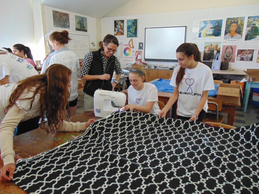 Hope Prockop (second from left) 40+ and 45+ 2015 U.S. national champion, helps other SquashCares volunteers complete the last stitch on one of the therapy blankets 